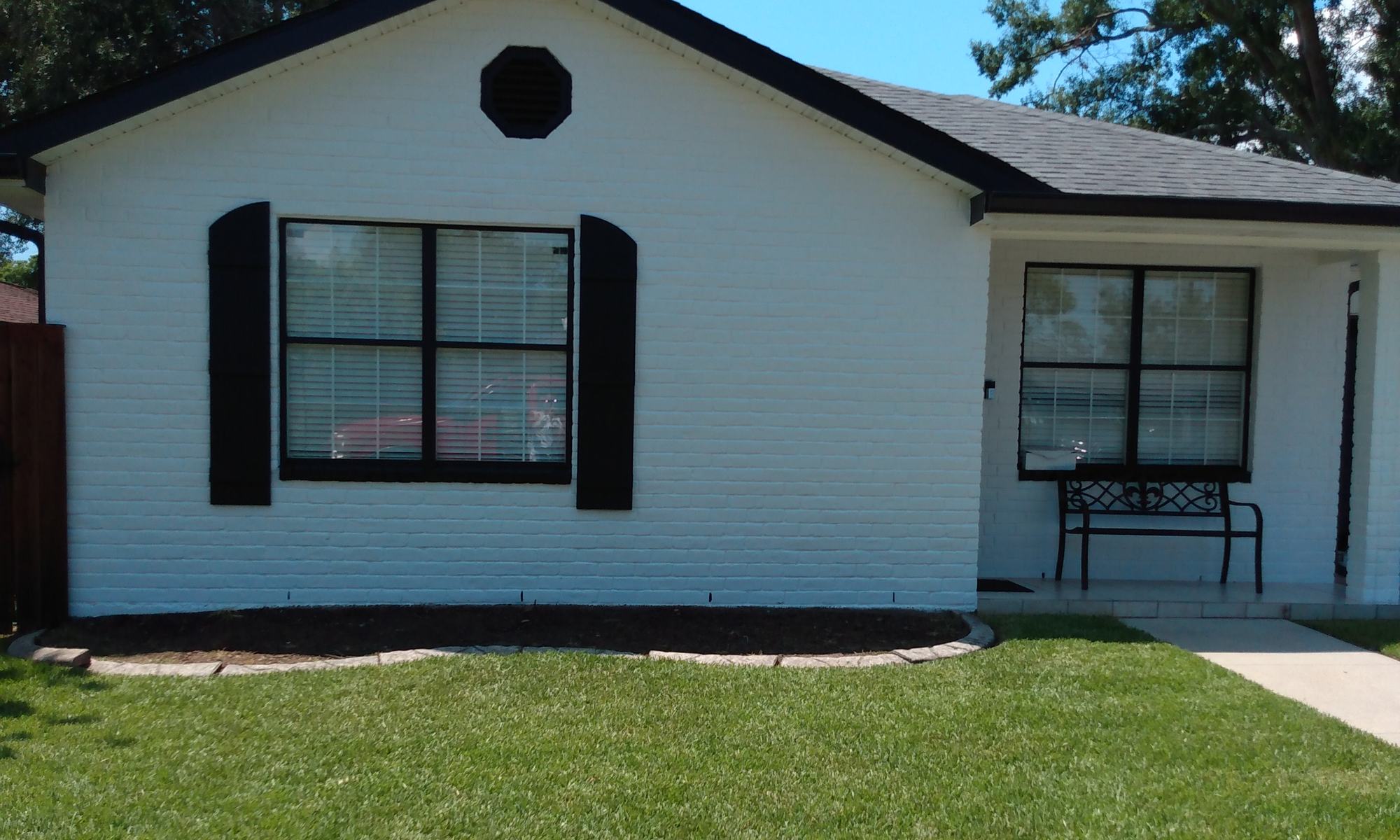 Brick home repainted white with black shutters and trim